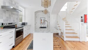 Una cocina moderna con armarios blancos, electrodomésticos de acero inoxidable y una isla central.