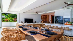 Un espace repas moderne avec une longue table en bois, dressée pour six personnes, entourée de chaises en osier.