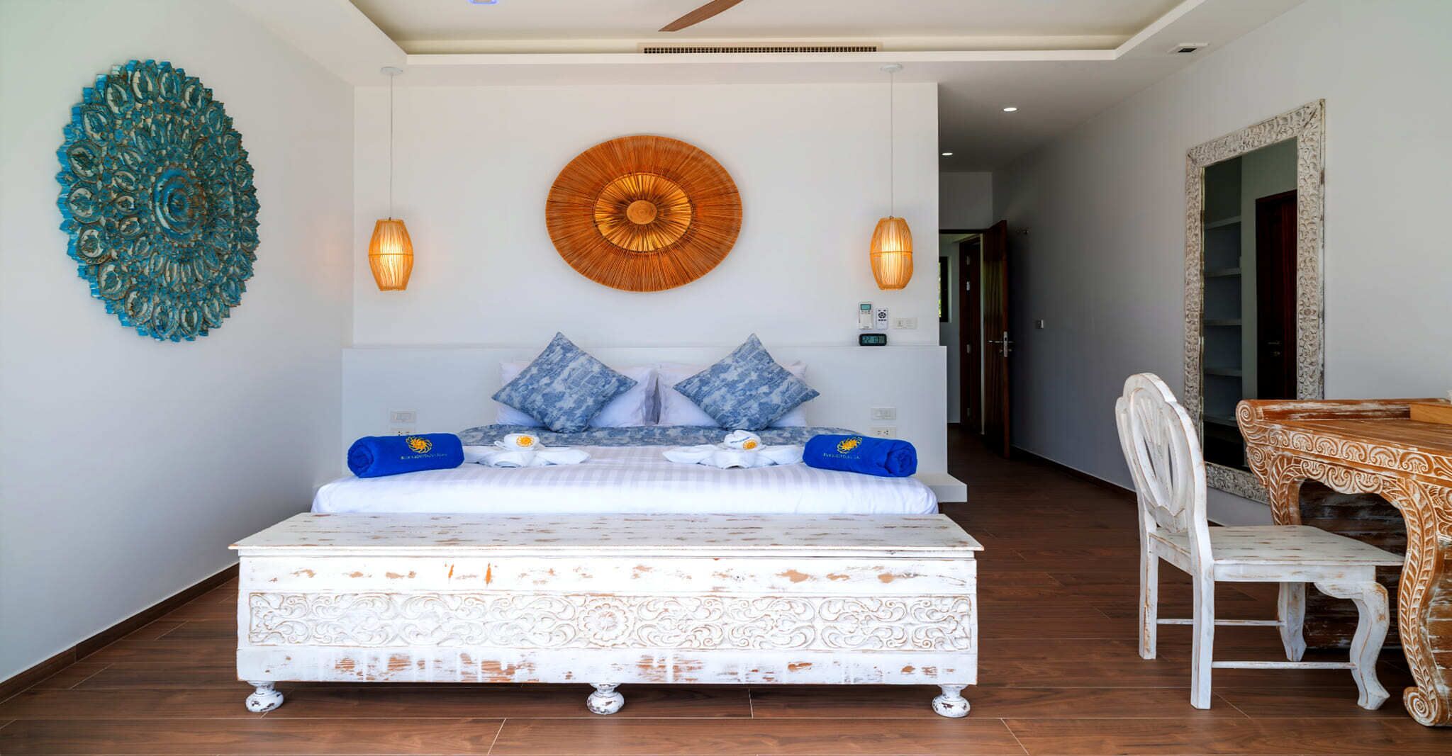 A bedroom with a large bed, two wall-mounted lamps, and a decorative wall piece.