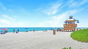 A beach with a lifeguard tower, beach chairs, umbrellas, and a clear sky. - Studio with Beach Access and Panoramic City View Miami! (Sunny Isles Beach)