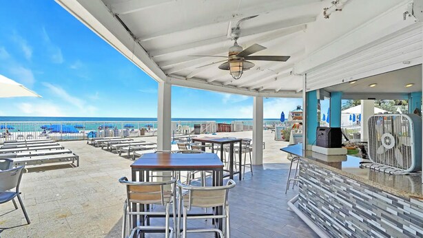 An outdoor patio with tables and chairs, a ceiling fan, and a view of the beach. - Studio with Beach Access and Panoramic City View Miami! (Sunny Isles Beach)