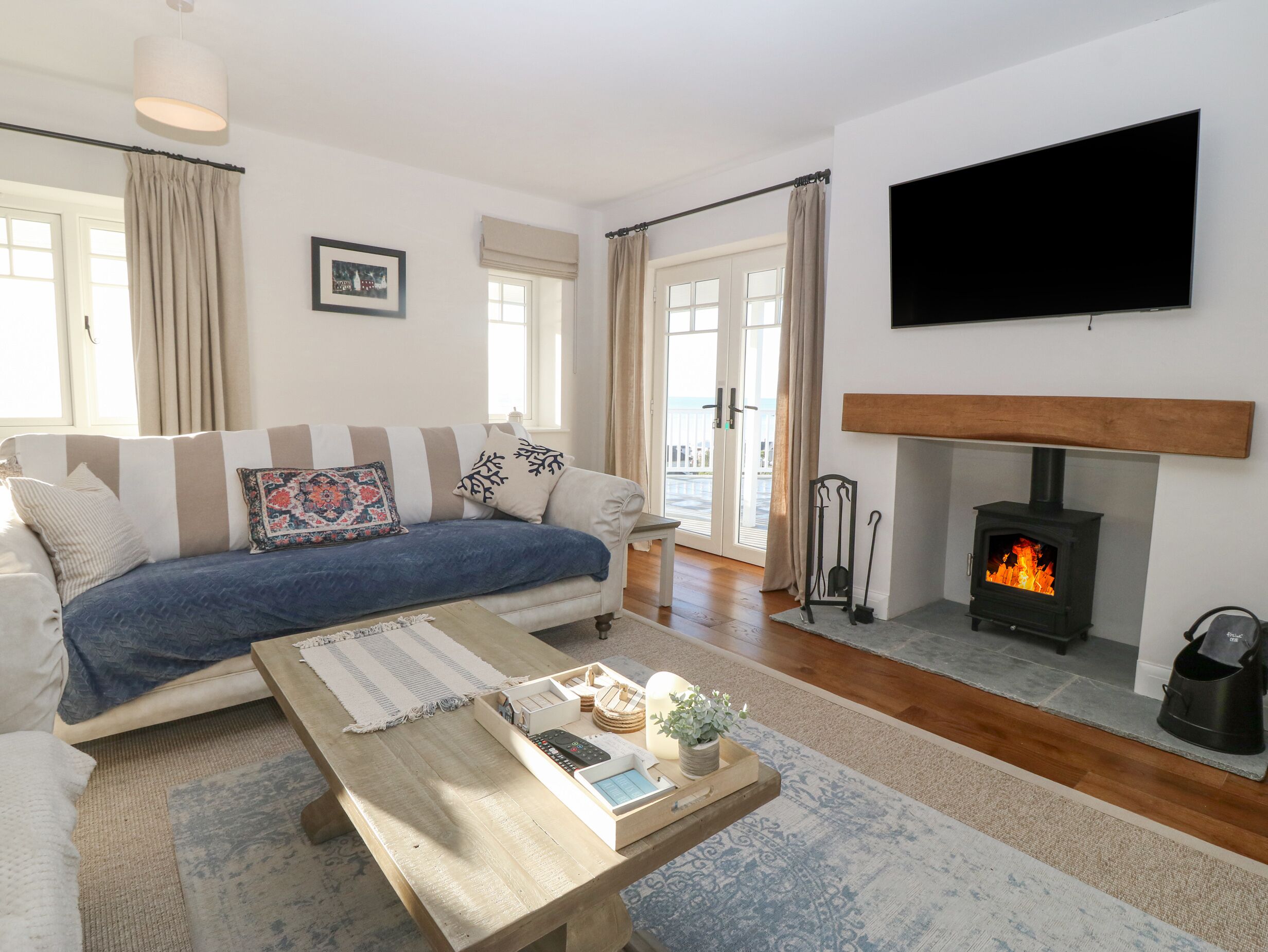 Ein Wohnzimmer mit einer Couch, einem Couchtisch, einem Kamin und einem an der Wand befestigten Fernseher.