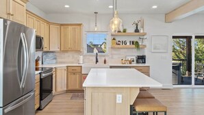 Una cocina moderna con armarios de madera, electrodomésticos de acero inoxidable, una isla central y vistas al exterior.