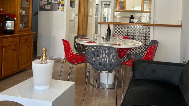 Una cocina moderna con armarios blancos, un comedor con mesa redonda y un sofá negro.
