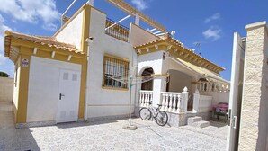 Un edificio con un patio empedrado, una bicicleta y una puerta blanca.