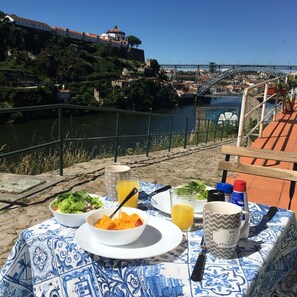 Une table dressée avec de la nourriture et des boissons, donnant sur une rivière avec un pont en arrière-plan.
