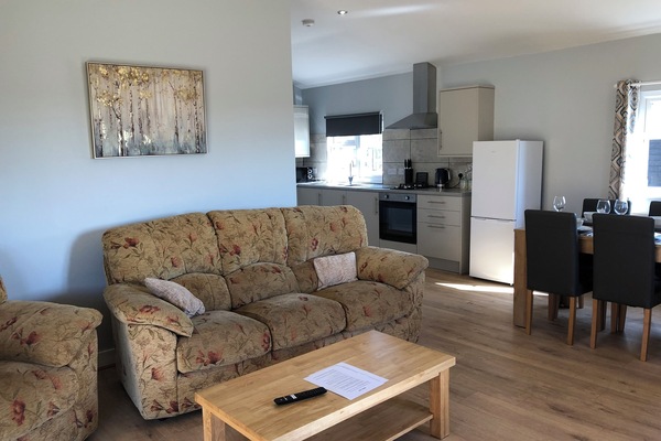 Spacious living area with dining table for four and well-equipped kitchen.