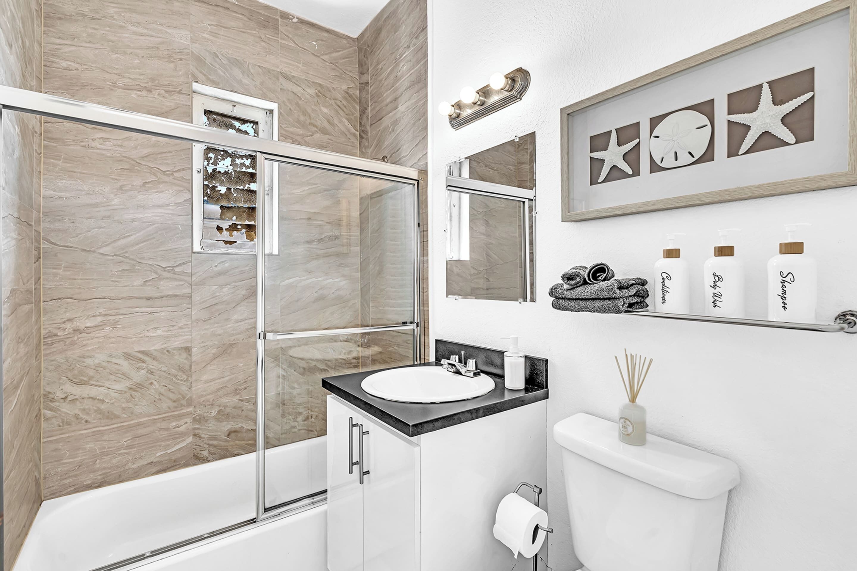Un bagno moderno con cabina doccia in vetro, lavandino bianco e water.