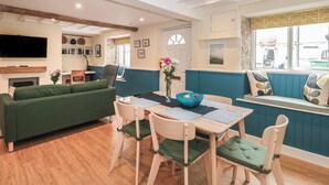 A cozy living room with a green sofa, wooden dining table, and blue accent walls. - Holly Cottage (Yeovil)