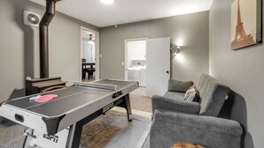 A living room with a ping pong table, a gray couch, and a painting of the Eiffel Tower. - Baycolt McCall - Pet friendly - Near downtown and golf course - Game room - Fenced yard (McCall)
