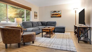 A modern living room with a sectional sofa, a coffee table, and a TV stand. - Baycolt McCall - Pet friendly - Near downtown and golf course - Game room - Fenced yard (McCall)