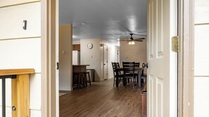 A hallway leading to a dining area with a ceiling fan, wooden flooring, and a clock on the wall. - Baycolt McCall - Pet friendly - Near downtown and golf course - Game room - Fenced yard (McCall)