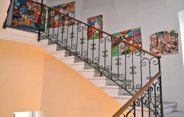 A staircase with ornate metal railings and colorful artwork on the walls. - Villa Ruscone (1643) near Lake Como (Lasnigo)