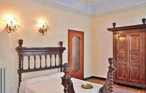 A bedroom with a wooden bed, a wardrobe, and two wall sconces. - Villa Ruscone (1643) near Lake Como (Lasnigo)