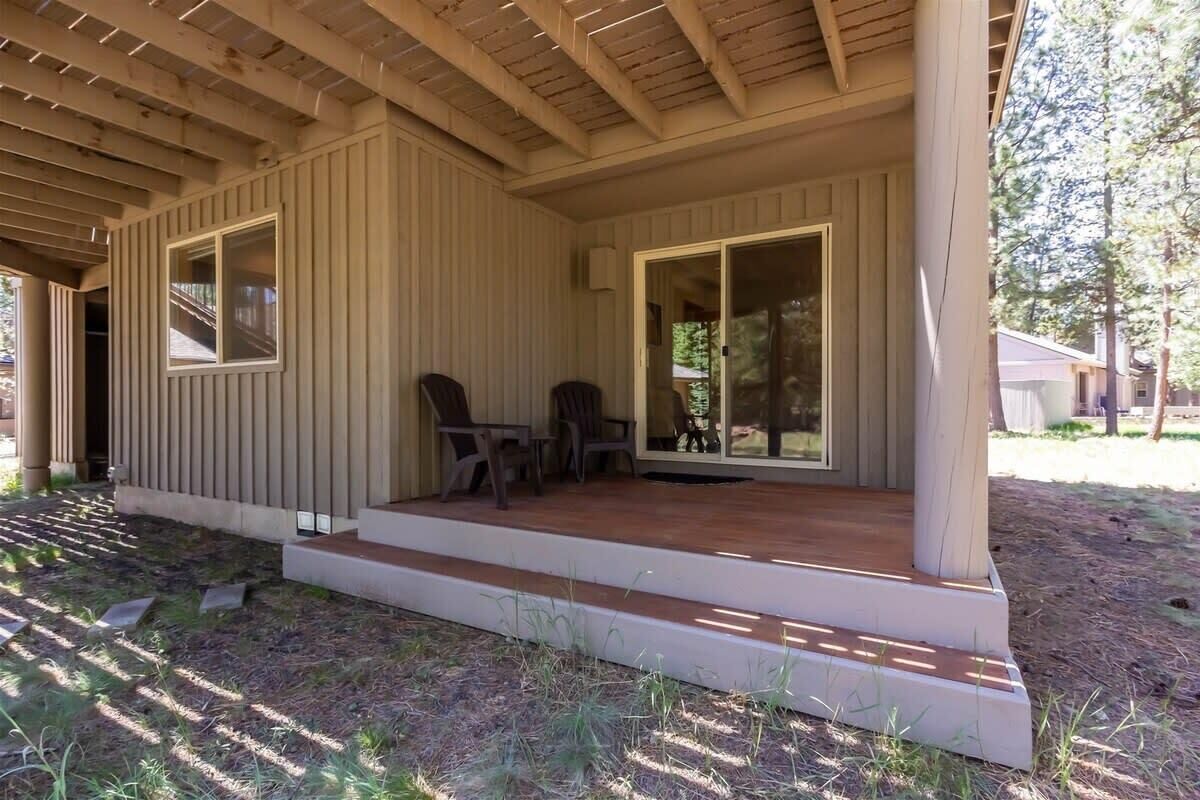 A covered outdoor area with a wooden deck, two chairs, and a table.