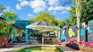 Un área de piscina con un pabellón, sillas de descanso y un bar.