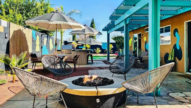 Un patio con un brasero, mobiliario exterior y una zona de estar techada.