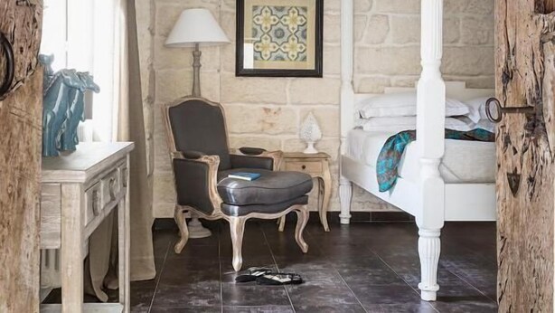 A bedroom with a four-poster bed, a chair, a desk, and a framed artwork on the wall. - Don Totu (San Cassiano)