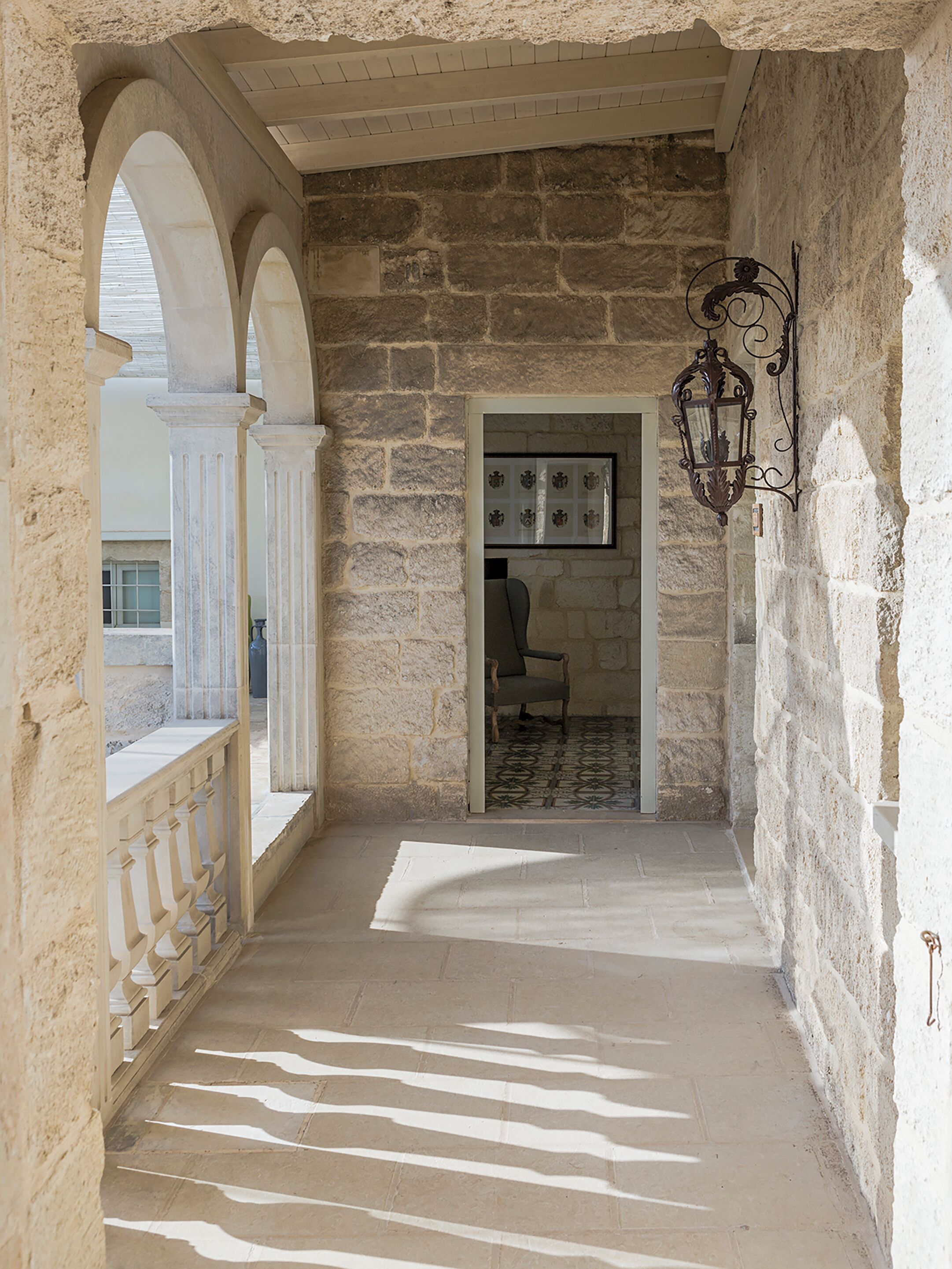 A corridor with stone walls, a wooden chair, and a framed picture on the wall.