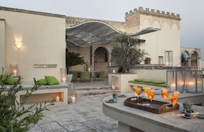 Un patio exterior con mobiliario, una zona de bar y vistas a un edificio histórico.