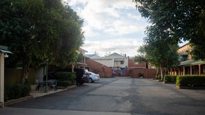 A residential street with parked cars, houses, and a gated entrance. - Yambil Inn Motel (Griffith)