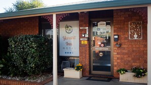 A Yambil Inn Motel with a reception area, a large bush, and a sign indicating office hours.