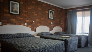 A hotel room with two beds, a brick wall, and a window with curtains. - Yambil Inn Motel (Griffith)
