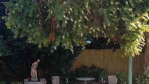 A patio area with a statue, two chairs, and a table. - Yambil Inn Motel (Griffith)