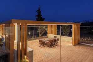 A covered outdoor dining area with a hexagonal tiled floor and a round table with chairs. - Villa Sandi with Private Pool (Heraklion)