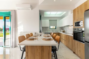 A modern kitchen with wooden cabinets, a built-in microwave, and an oven. - Villa Sandi with Private Pool (Heraklion)