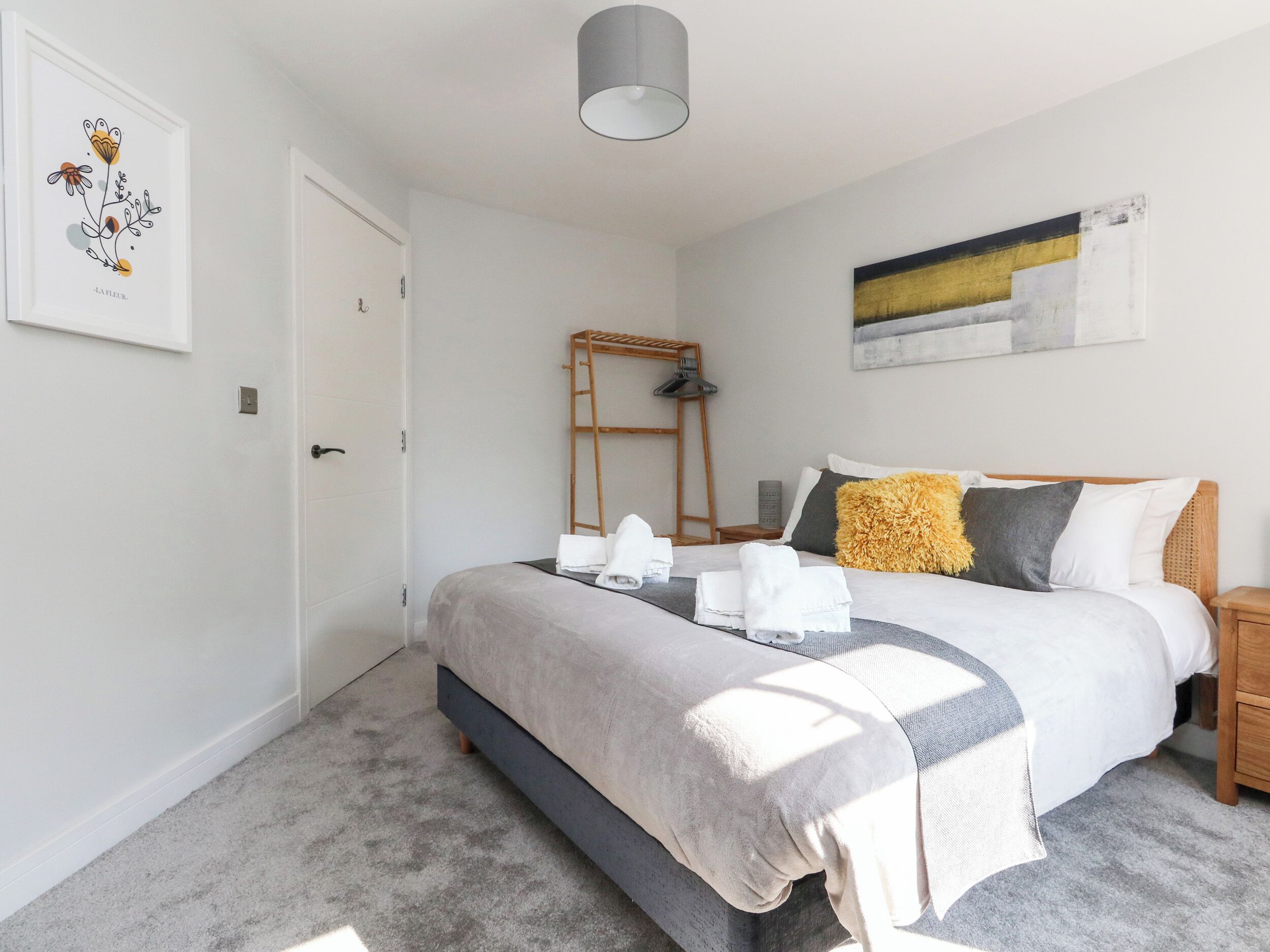 A neatly arranged bedroom with a bed, a ladder, and a painting on the wall.