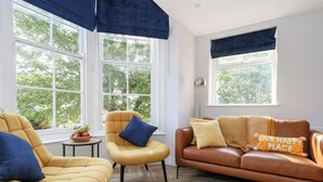 A living room with two yellow armchairs, a brown leather sofa, and a round woven rug. - Flat 6, Thornlow Heights (Weymouth)