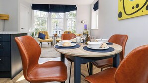 A dining area with a round table, four brown leather chairs, and a bottle of wine. - Flat 6, Thornlow Heights (Weymouth)