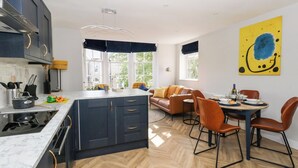 A modern kitchen with dark cabinets, a marble countertop, and a herringbone floor pattern. - Flat 6, Thornlow Heights (Weymouth)