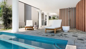 A modern outdoor pool area with lounge chairs, a seating area, and a wooden privacy screen. - Absolute Beachfront Luxury Apartment (Coolum Beach)
