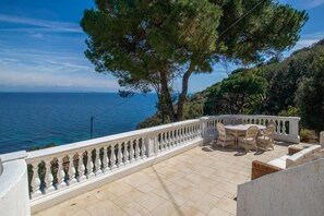Une terrasse dotée d’une balustrade blanche, de mobilier d’extérieur et offrant une vue sur la mer.