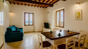 A cozy room with a wooden ceiling, a dining table with chairs, a sofa, and a TV on a stand. - Villa Porticciolo has an heartbreaking view. (Rio Marina)