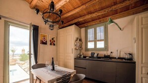 A modern kitchen with a wooden ceiling, a dining area with a table and chairs, and a view of the cityscape through the window. - 1 Bedroom Apartment in Caltagirone (Caltagirone)