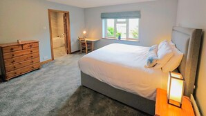 Une chambre à coucher comprenant un lit, une commode, un bureau, une chaise et une fenêtre donnant sur un beau paysage.