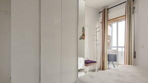 A bedroom with a bed, a wardrobe, a chair, and a window with curtains. - Horizonte - Sea view by HD PROPERTIES (Quarteira)