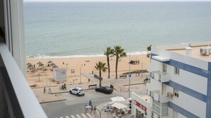 A beach view from a building with a view of the sea, palm trees, and beach umbrellas. - Horizonte - Sea view by HD PROPERTIES (Quarteira)