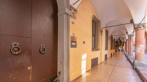 A corridor with arched ceilings, a tiled floor, and a door with a metal handle.