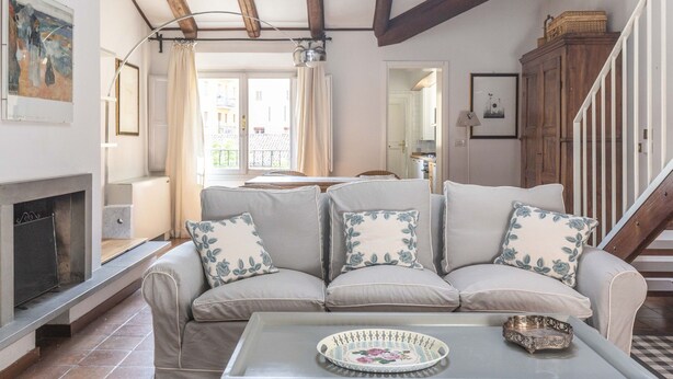 A living room with a sofa set, a fireplace, and a staircase.