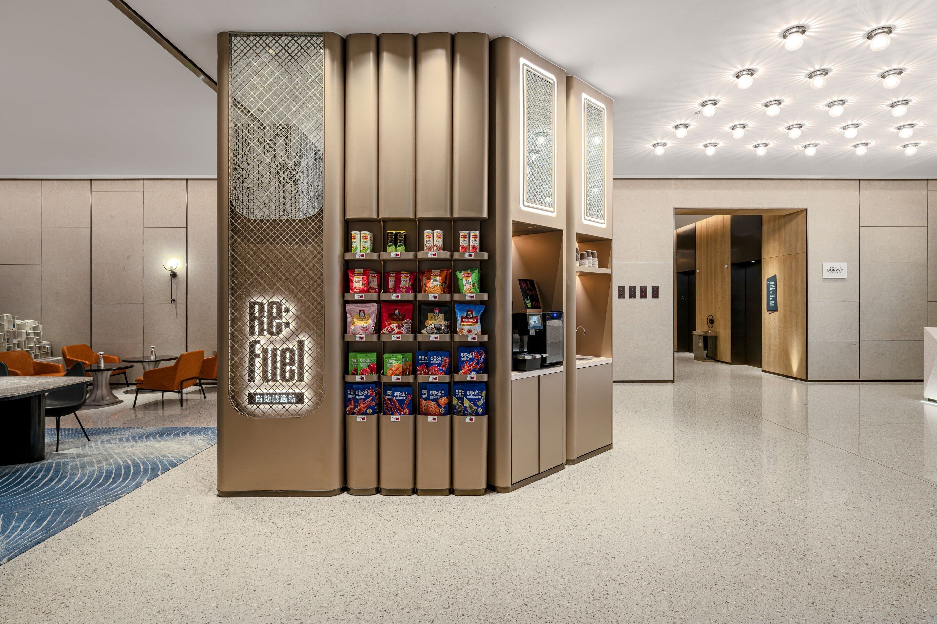 A modern hotel lobby with a self-service snack station featuring various packaged snacks.