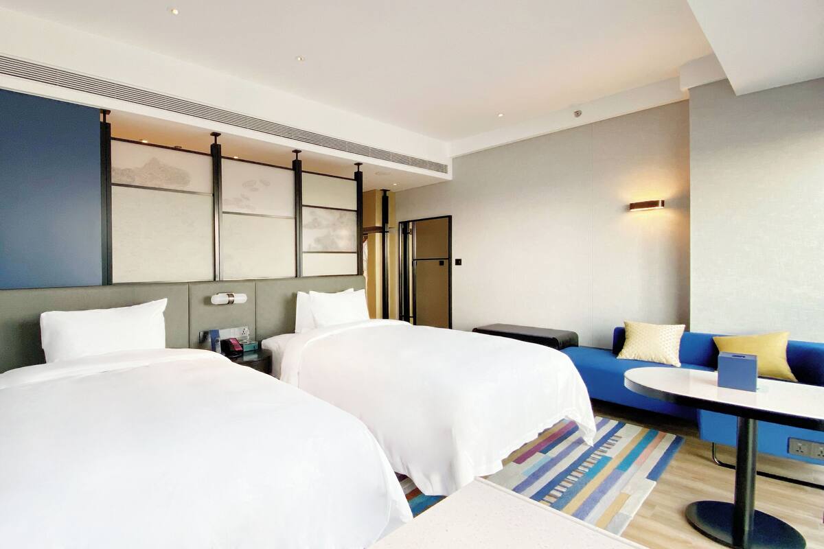 Una habitación de hotel con dos camas, un sofá, una mesita y un escritorio.