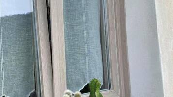 Un alféizar con un cartel de 'WELCOME' y dos cactus en una cesta de metal.