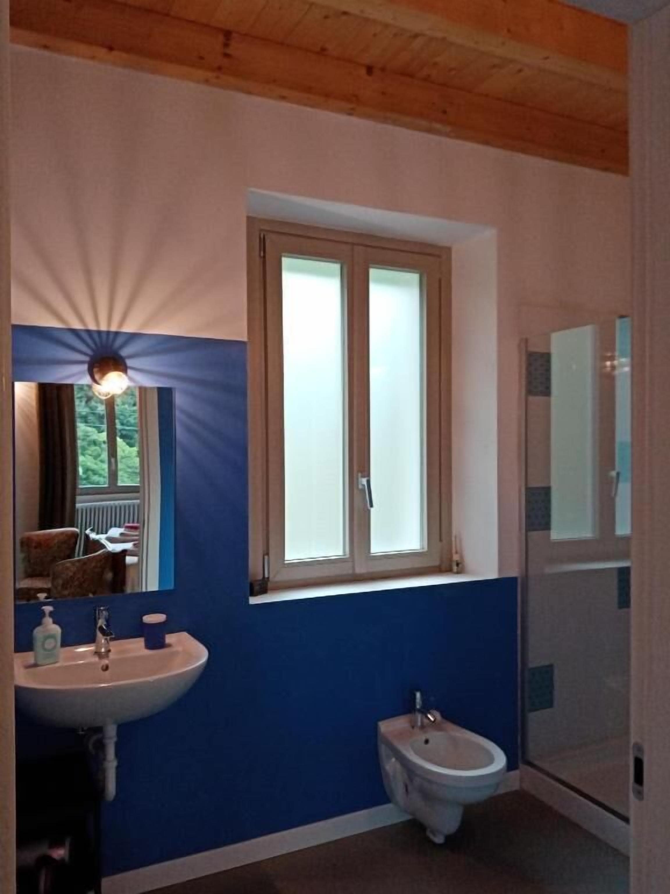 A bathroom with a sink, toilet, and window.