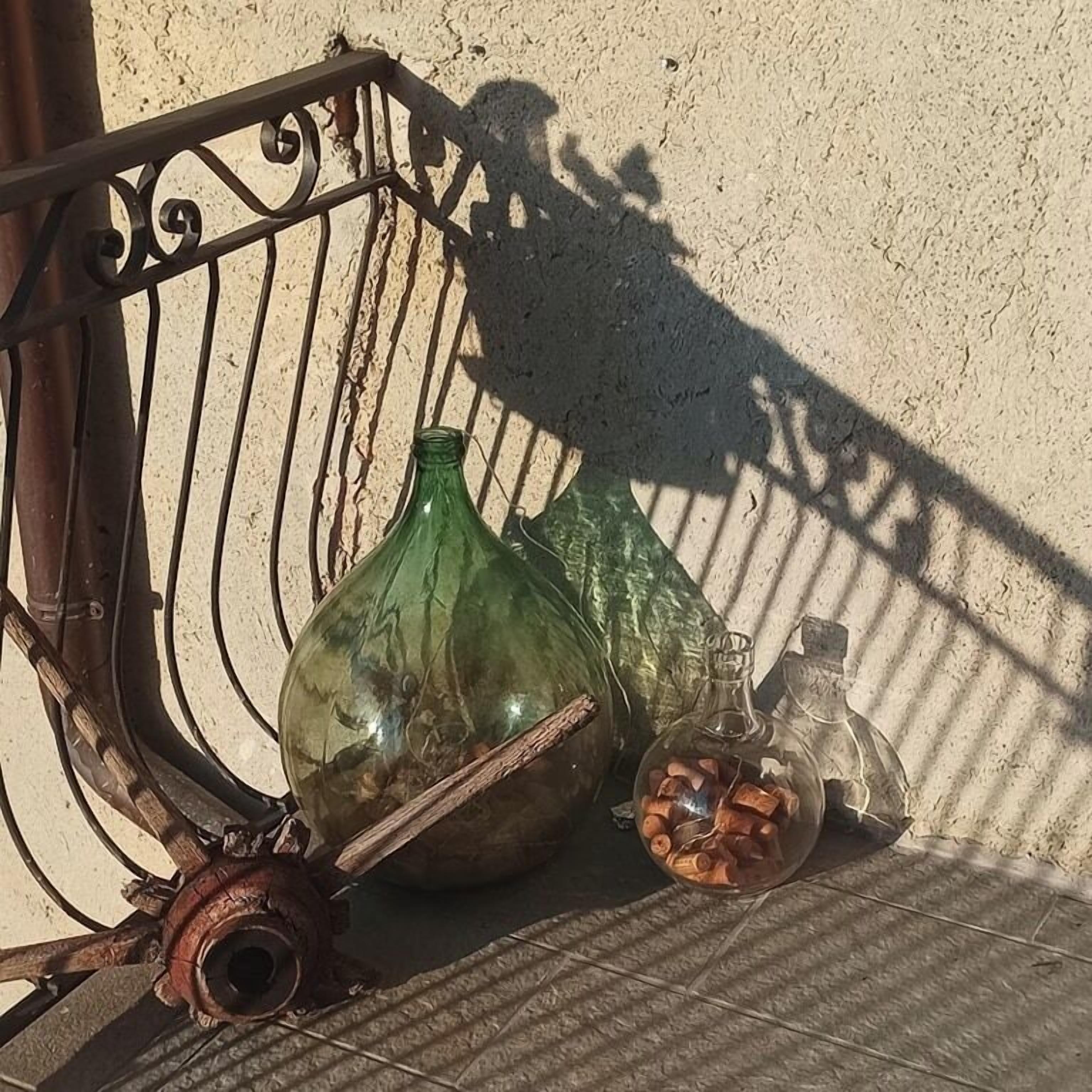 Una sedia di metallo con una bottiglia verde e un piccolo barattolo con tappi su una superficie piastrellata.