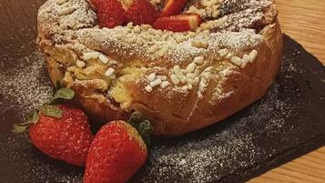 Ein Dessert mit Erdbeeren und Puderzucker auf einer Schieferplatte.