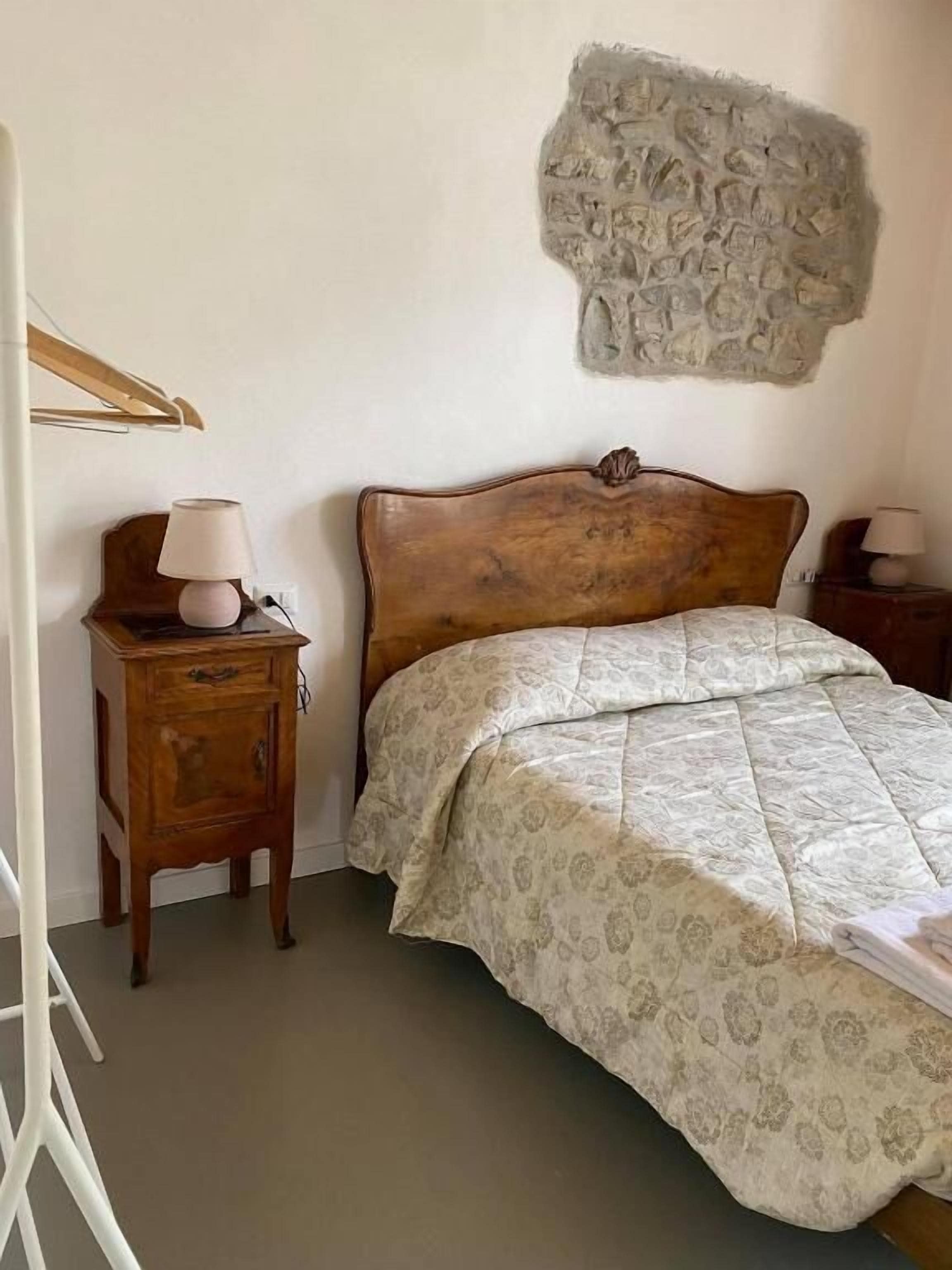 Ein Schlafzimmer mit einem hölzernen Bett, einem Nachttisch mit Lampe und einer Wanddekoration aus Stein.
